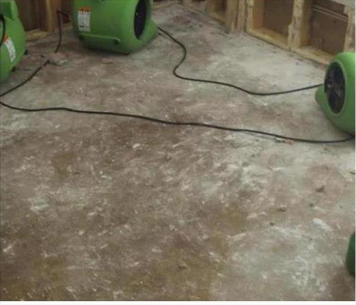 concrete pad, no carpet, wall framing visible with air movers